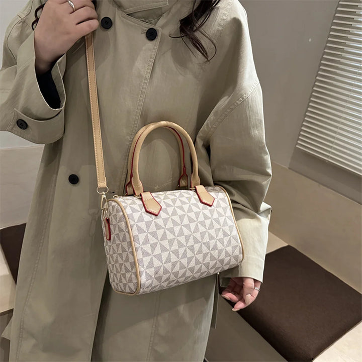 White geometric triangle print PU handbag with top handles and adjustable strap on a coat