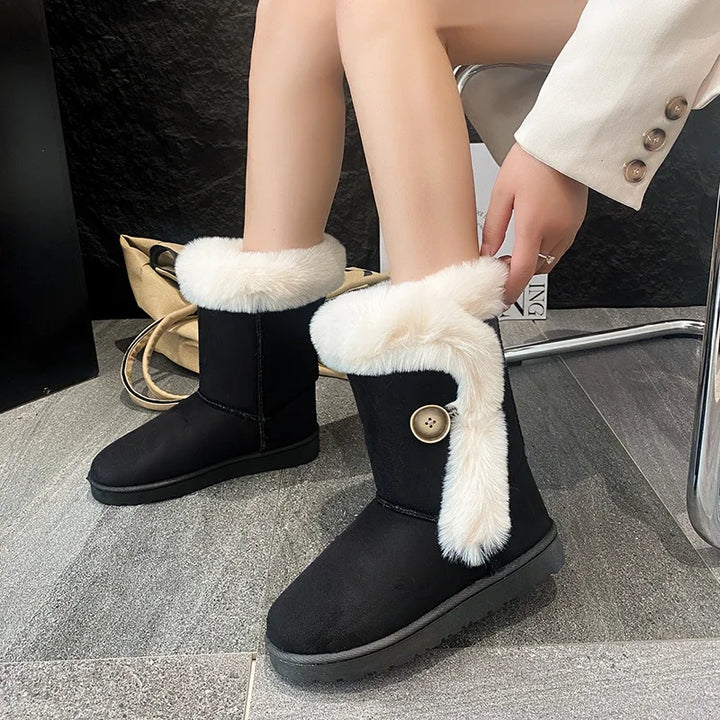 Black snow boots with white fur trim worn by a person indoors.
