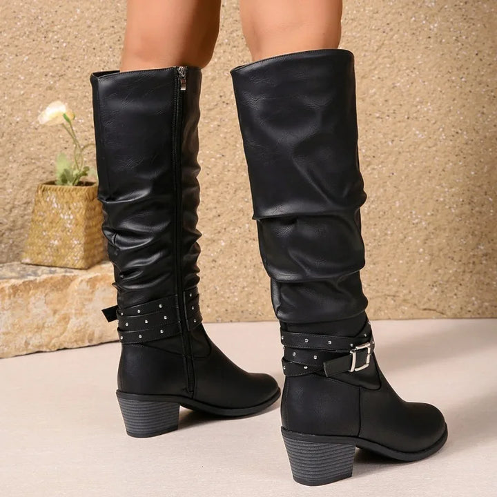 Black knee-high boots with buckles on a neutral background