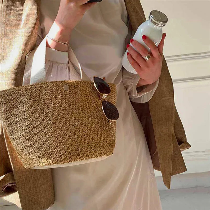 Beige woven straw bucket handbag with buttoned front and black sunglass-style accents
