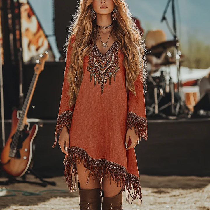 Woman in a bohemian dress with fringe standing in front of musical instruments.