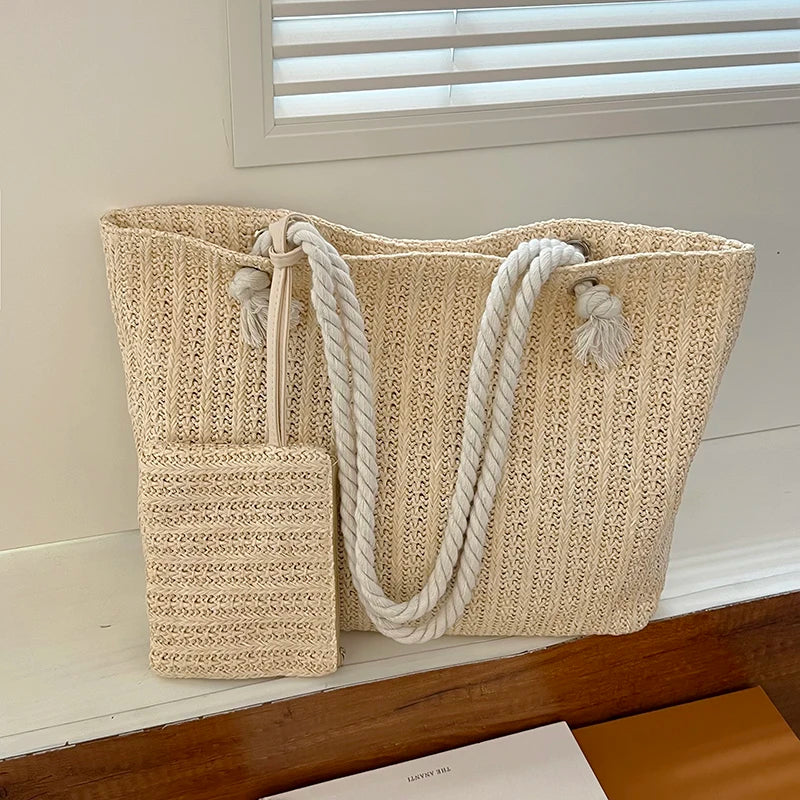 Beige woven tote bag with rope handles on a wooden surface.