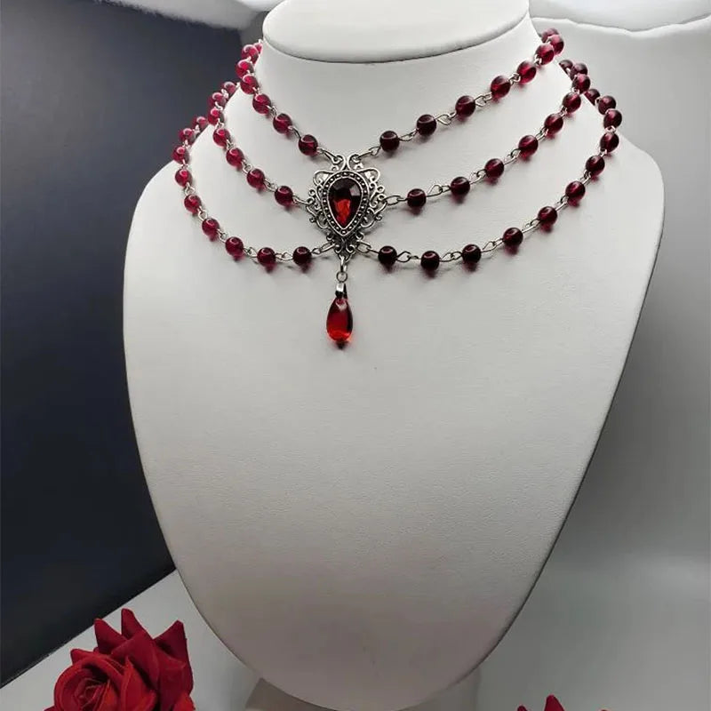 Vintage gothic necklace on mannequin: layered dark red bead chains and red teardrop pendant