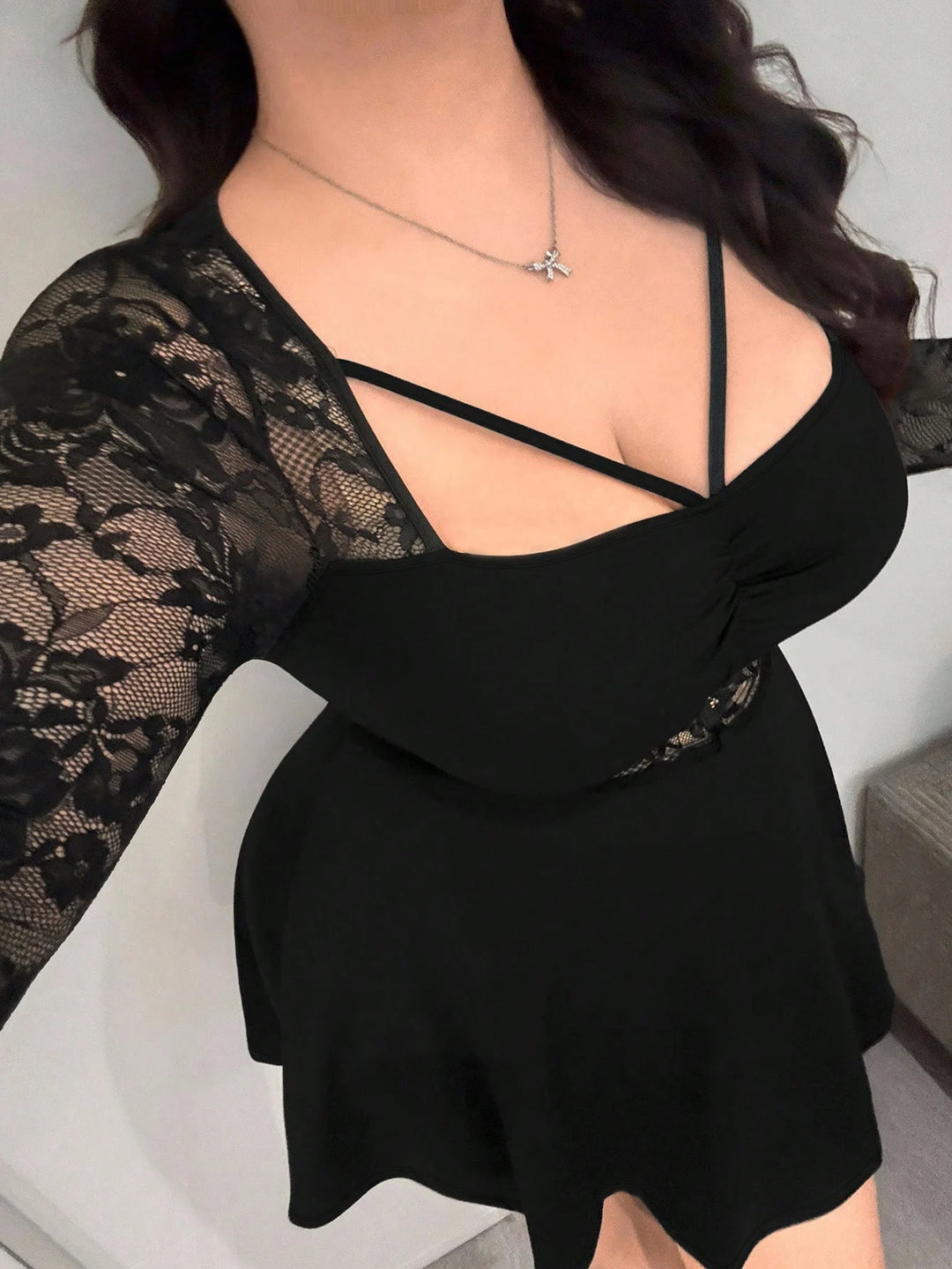 Black mini dress with lace sleeves and crisscross straps over V-neck