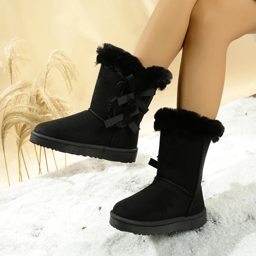 Black mid-calf suede snow boots with plush cuff, bow straps, and chunky platform