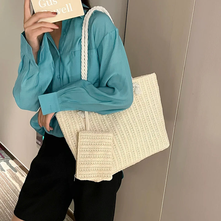 Person holding a beige woven bag with a plain background