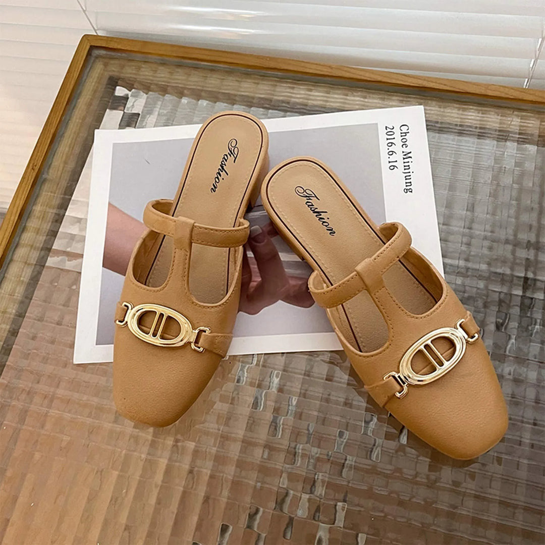 Pair of tan shoes with gold buckles on a textured surface