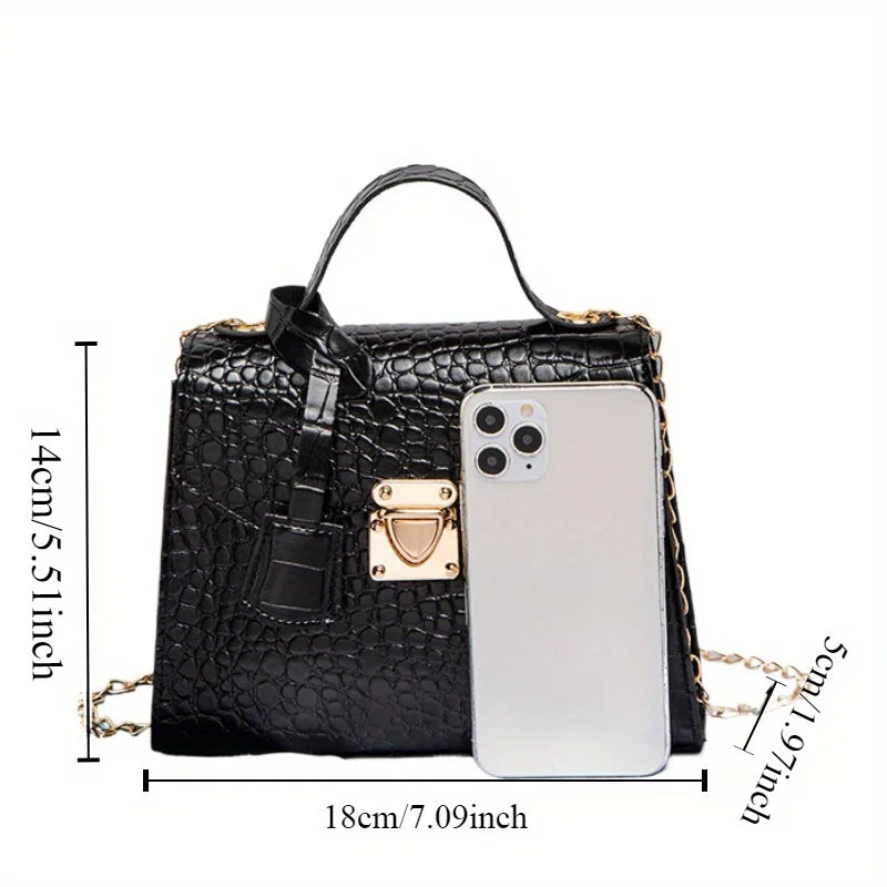 Black textured handbag with gold accents and a phone for scale on a white background