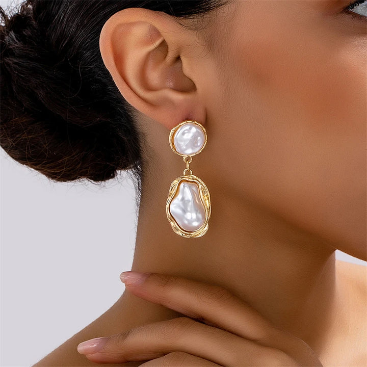 Pearl earring worn by a person on a plain background