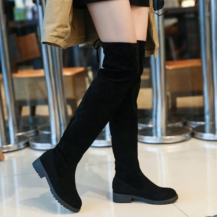 Person wearing black over-the-knee boots in a casual setting.