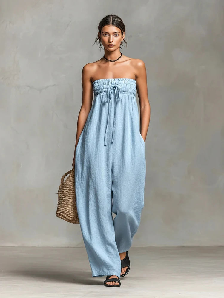 Woman wearing a light blue strapless jumpsuit against a gray background
