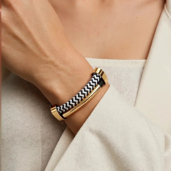 Gold bracelet with black and white pattern worn on a wrist against a neutral background