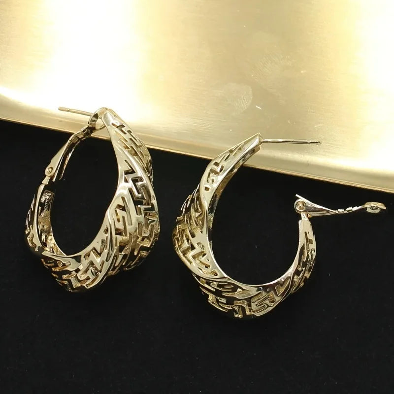 Gold hoop earrings and a matching pendant on a beige fabric background