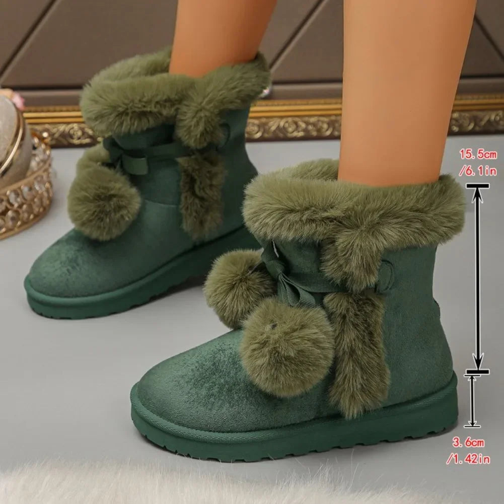 Green faux-fur ankle boots with bow and pom-pom details, shown on a doll's legs against a neutral indoor background.