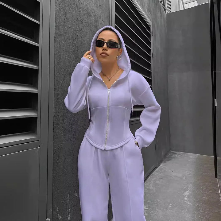 Person wearing a light purple tracksuit standing in an urban setting.