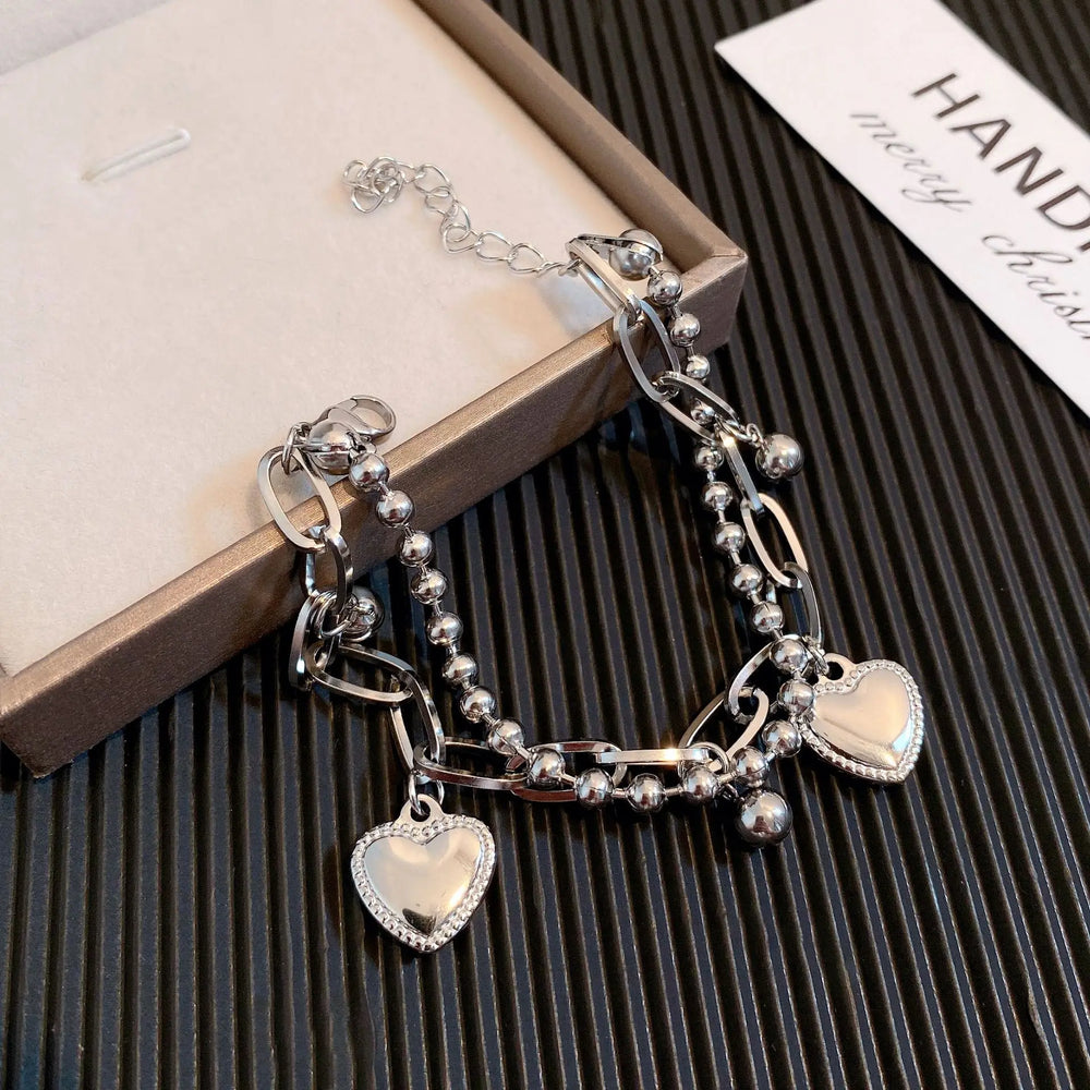 Silver bracelet with heart charms in a box, brand name visible