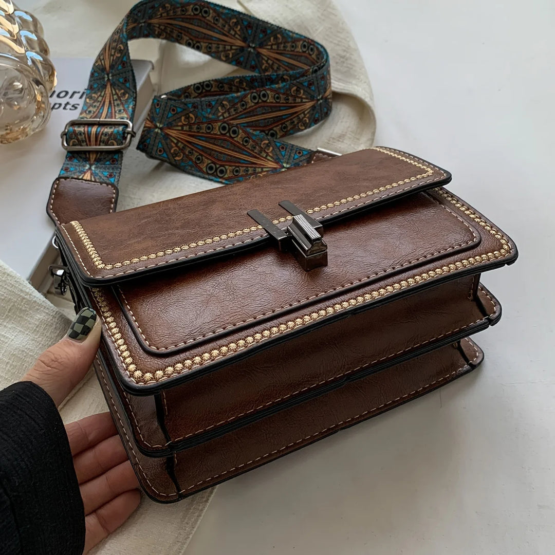 Mini crossbody bag in brown with flap lock, beaded edge trim, and patterned strap