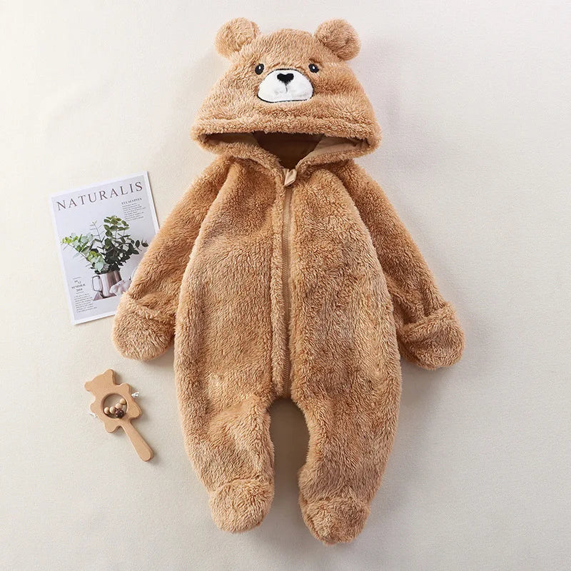 Brown bear-themed baby onesie on a light background with a magazine and wooden toy.