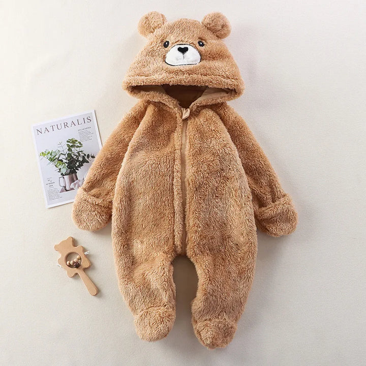 Brown bear-themed baby onesie on a light background with a magazine and wooden toy.
