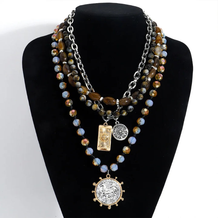 Layered beaded necklace with dark blue, tiger-eye and iridescent beads; square and coin charms