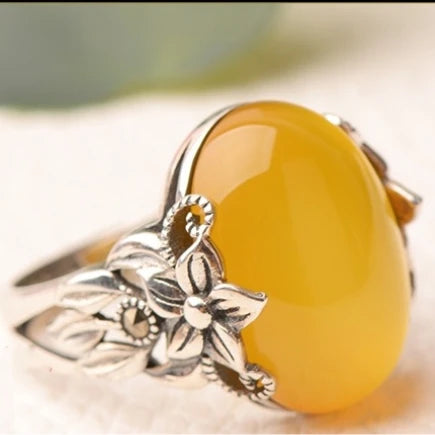 Ring with a yellow stone and silver leaf design on a light background