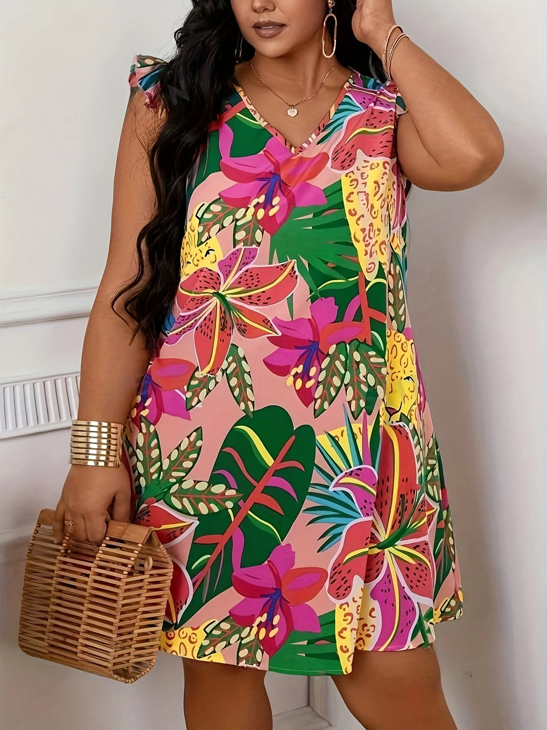 Woman wearing a colorful floral dress holding a woven bag indoors.