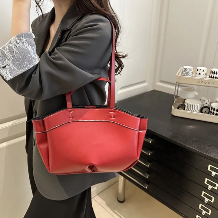Person holding a red handbag in an indoor setting