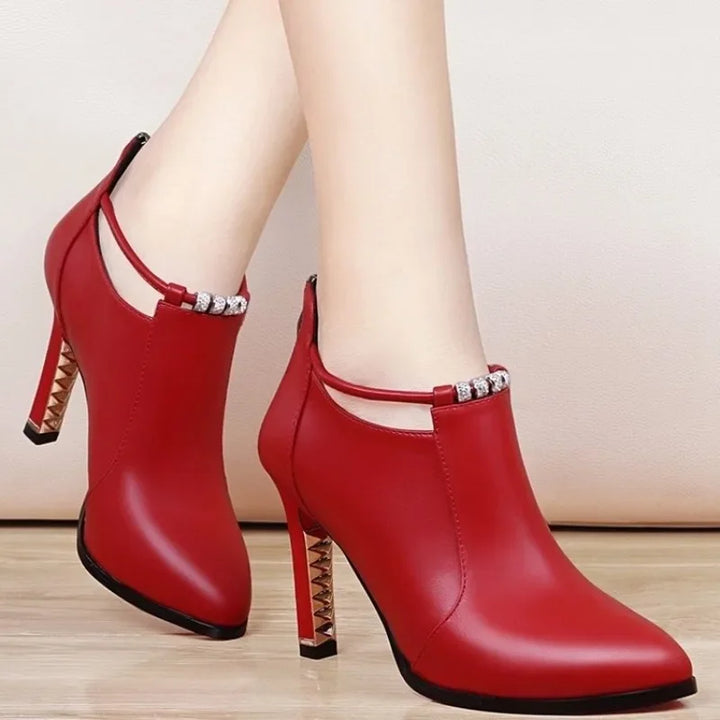 Red high-heeled shoes with studded details on a light wooden floor.