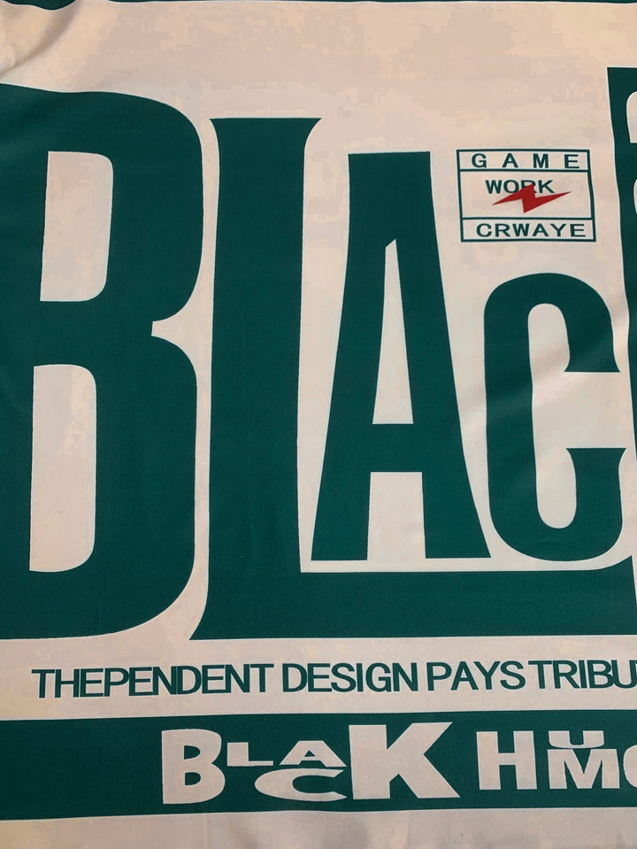 T-shirt close-up of large dark green lettering on cream with “BLACK HUMOR” band