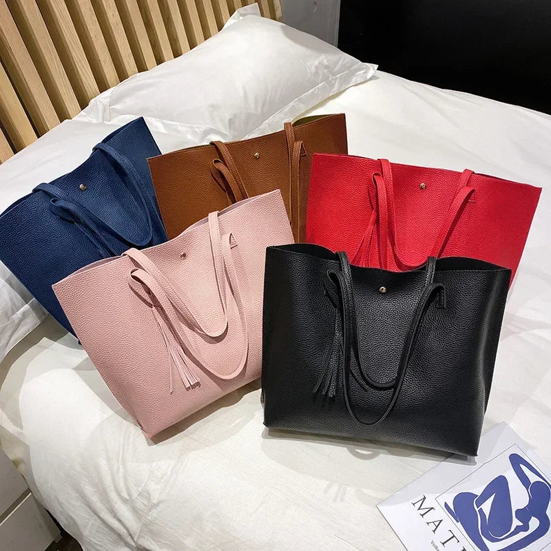 Five handbags in blue, brown, pink, red, and black on a white surface.