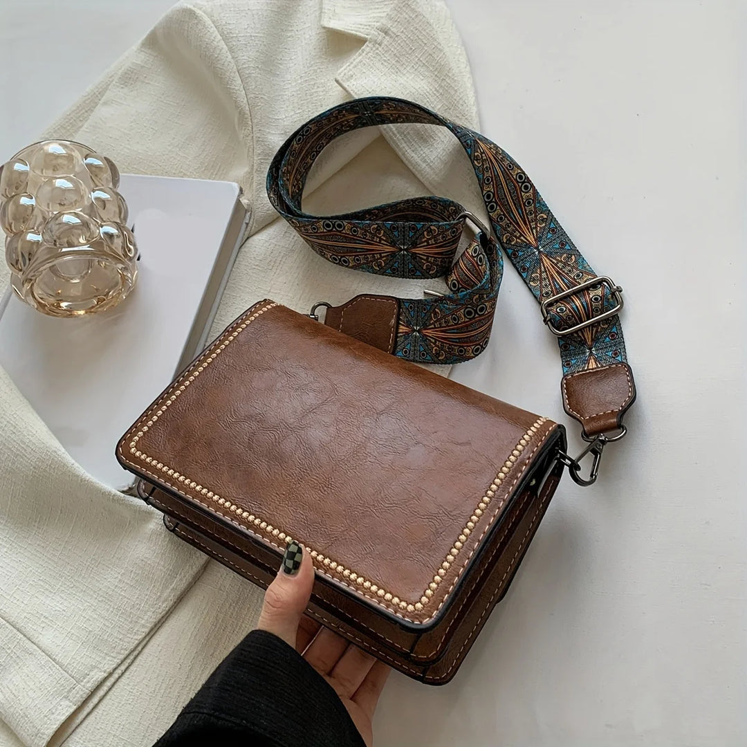 Brown leather mini crossbody bag with beaded edge trim and patterned adjustable strap