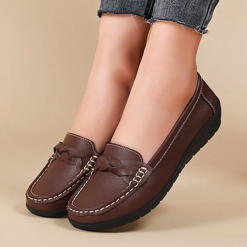 Brown loafers worn with denim jeans on a beige background