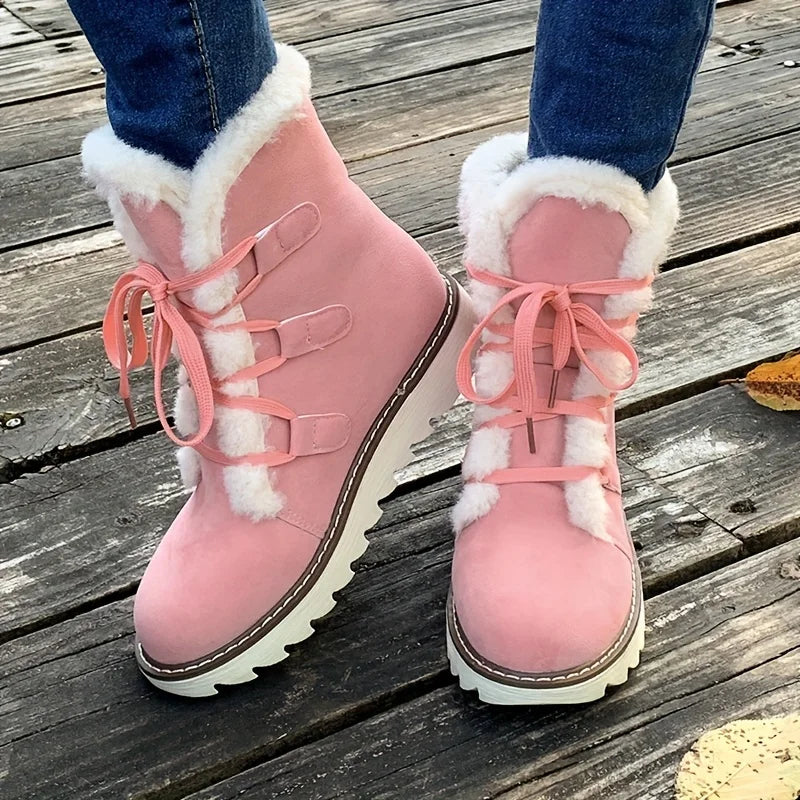 Pink winter boots with white fur lining on a wooden floor