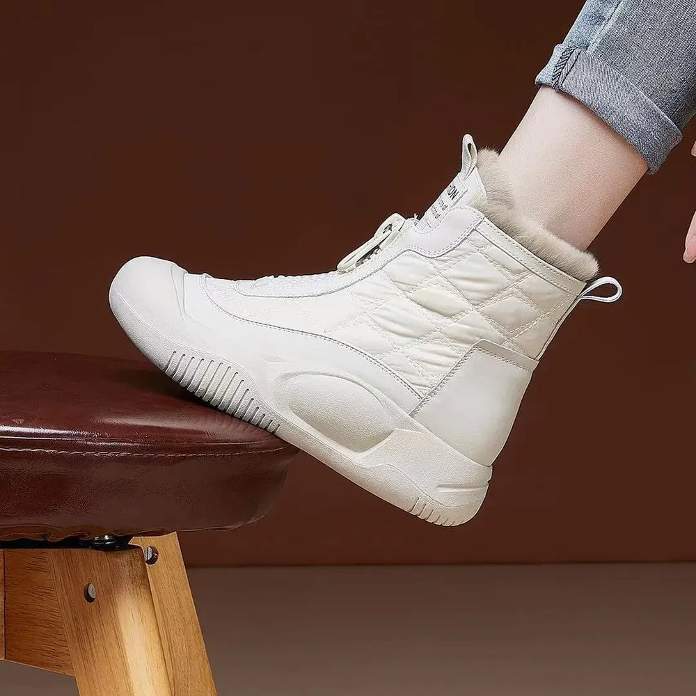White high-top sneakers worn by a person sitting on a brown stool against a brown background