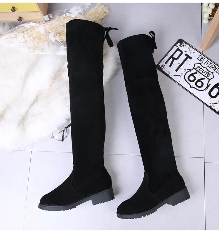 Black knee-high boots on a light background with a vintage license plate.