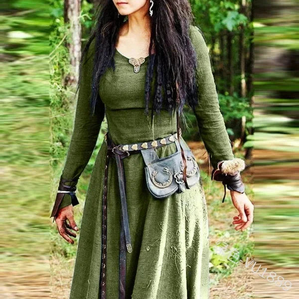 Person in a green dress with a belt and pouch standing in a forest setting