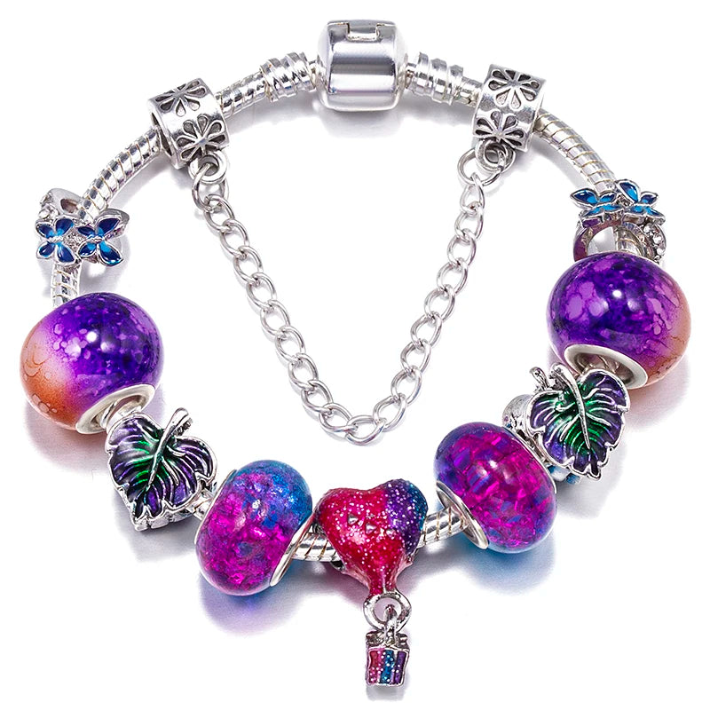 Silver charm bracelet with purple glitter beads, blue bow charms, and a hanging key charm