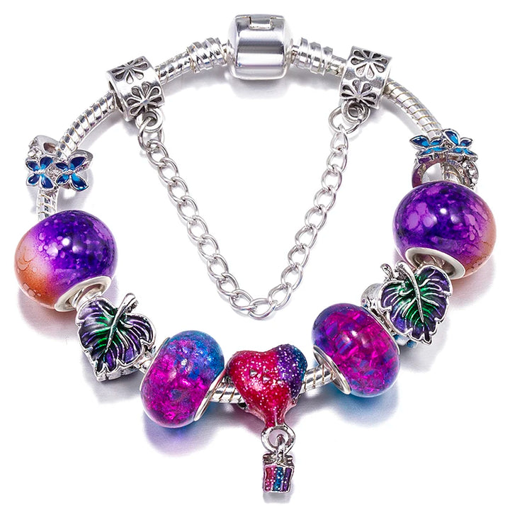 Silver charm bracelet with purple glitter beads, blue bow charms, and a hanging key charm