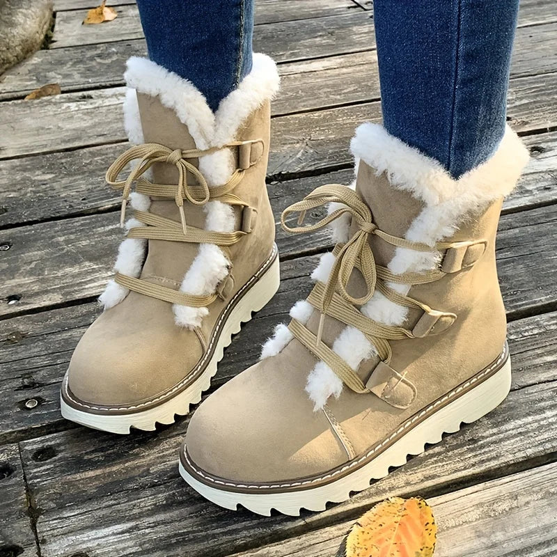 Beige winter boots with white fur trim worn on a wooden floor.