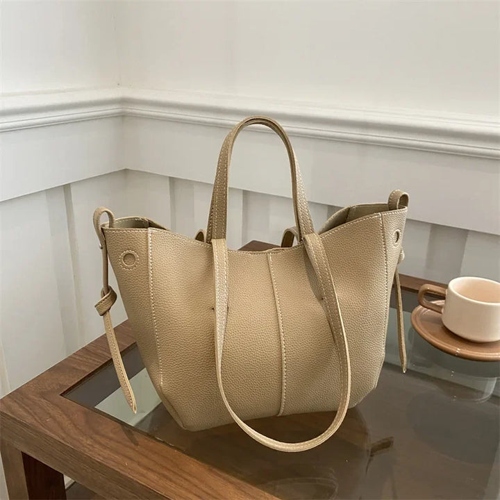 Beige handbag on a reflective surface with a neutral background