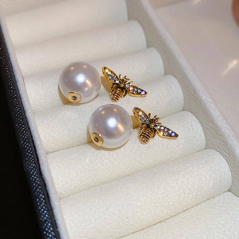 Hand wearing a decorative ring with a bee design on a neutral background