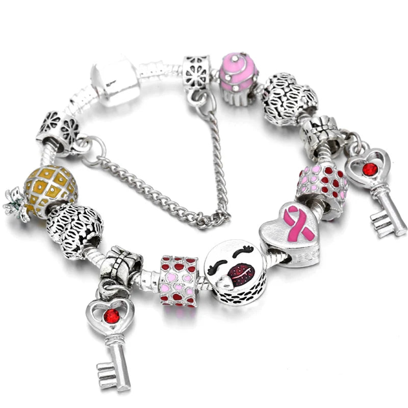 Silver-tone charm bracelet with pink ribbon heart and red-stone bow charm
