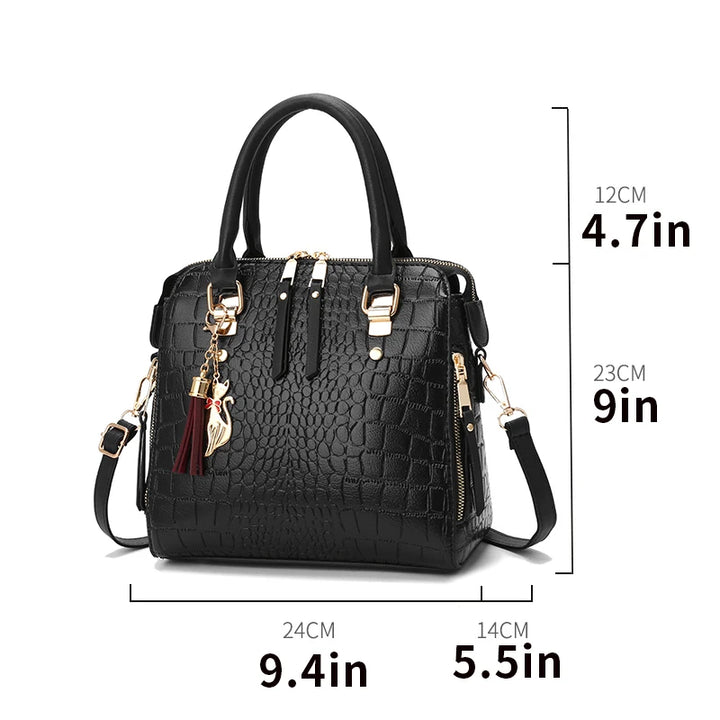 Black crocodile-embossed tote bag with top handles, shoulder strap, and gold buckles