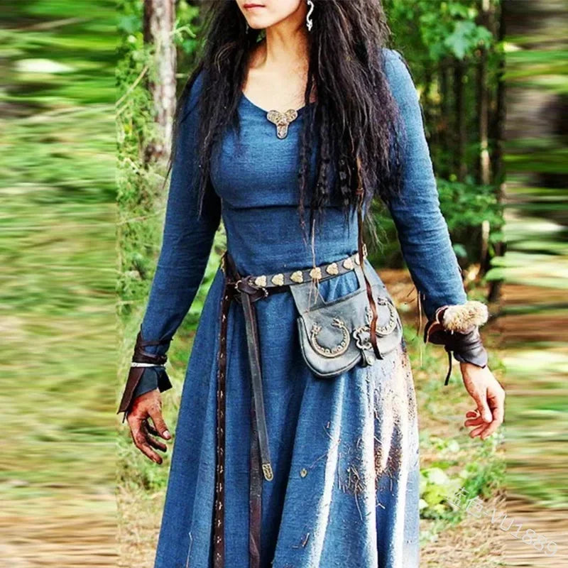 Person in a blue medieval-style dress with accessories standing in a forest.