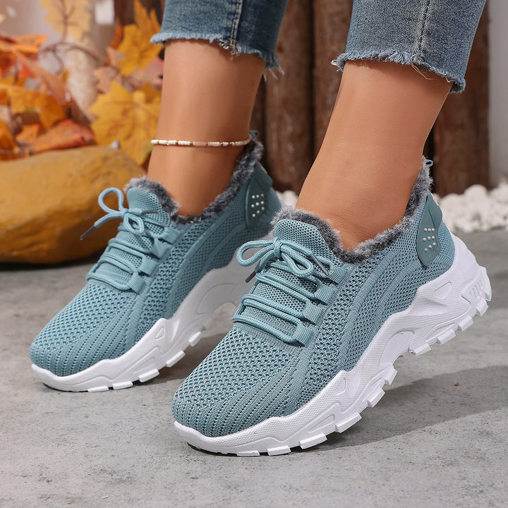 Women’s sky blue lace-up snow sneakers with plush gray lining, worn with jeans