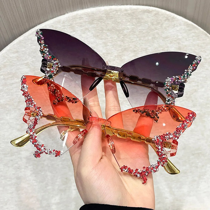 Sunglasses with decorative embellishments held by a hand on a light background