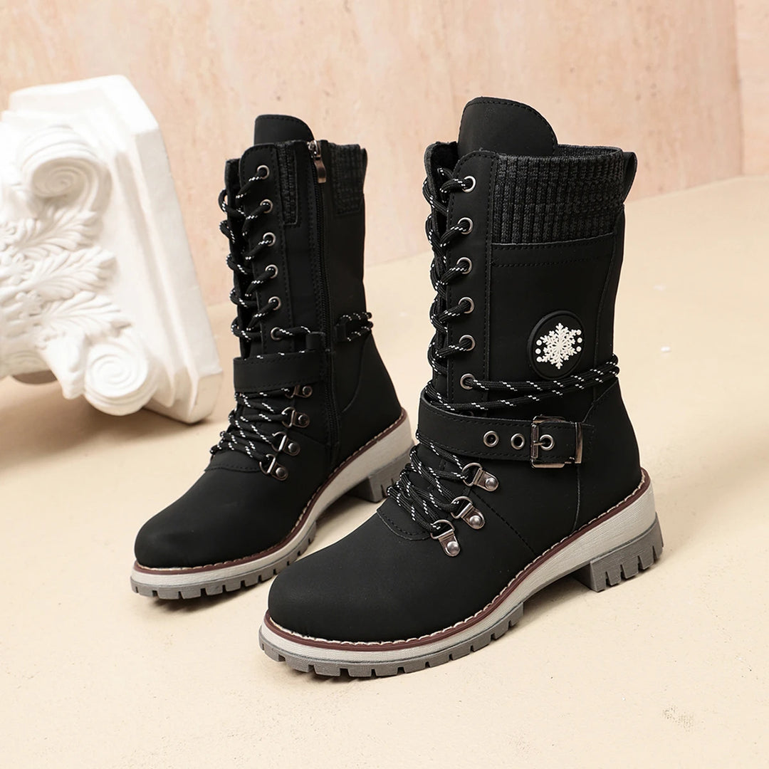 Women’s black winter boots with lace-up front, decorative snowflake badge, and tread sole.