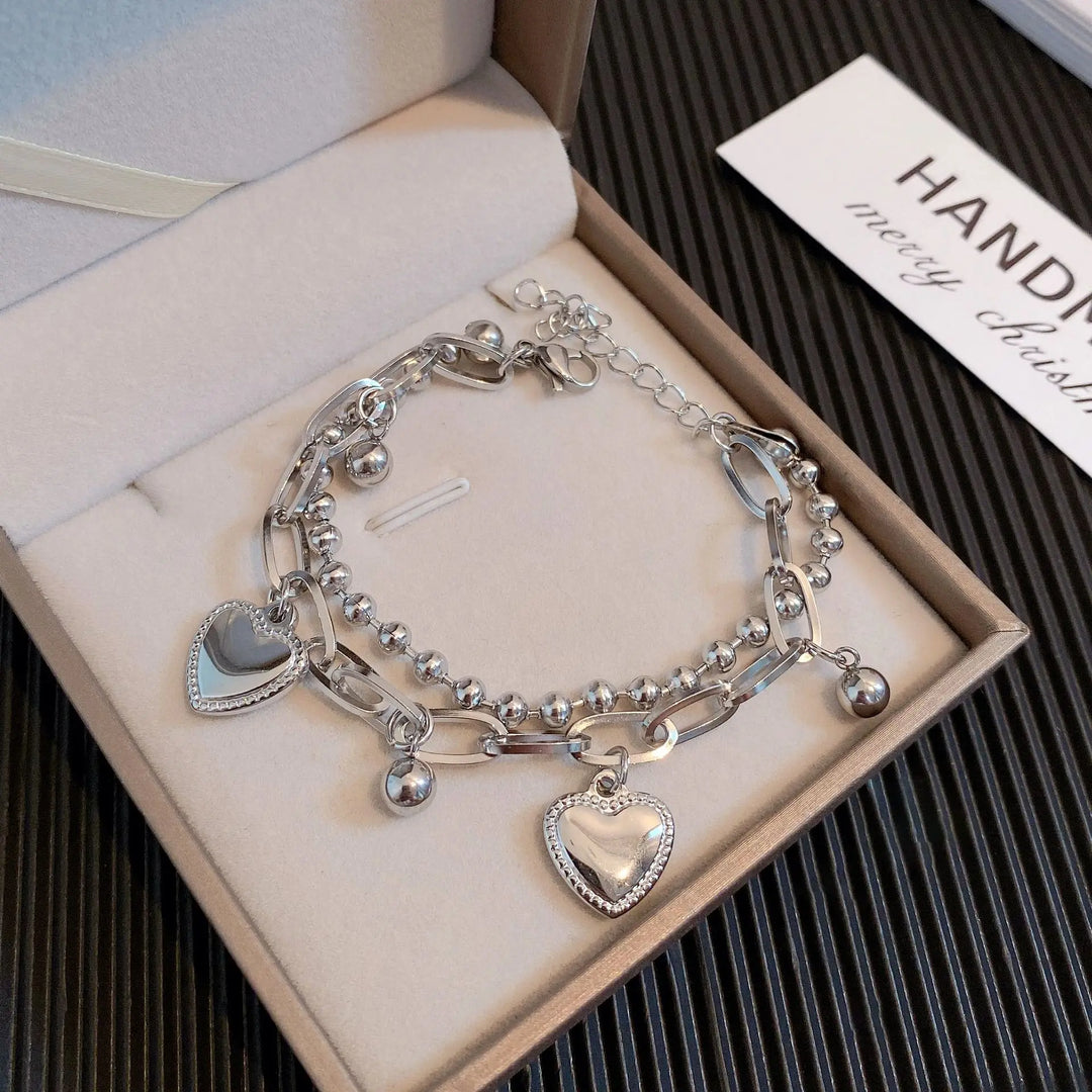 Silver bracelet with heart charms in a box, brand name visible