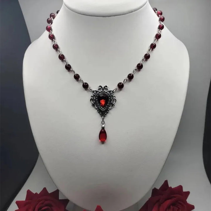 Gothic dark red bead necklace with ornate shield pendant and hanging red teardrop charm