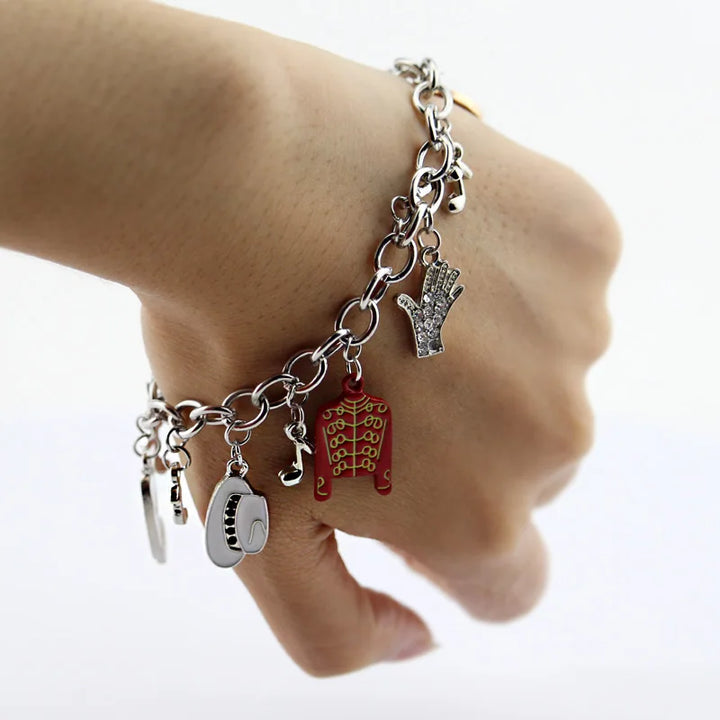 Silver-tone charm link bracelet on wrist with red jacket, shoe, crystal hand, round coin